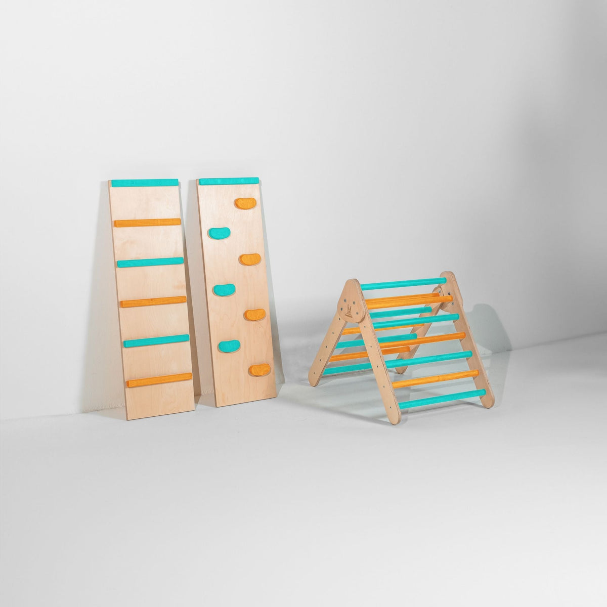 Small teal and orange climbing triangle beside upright ladder and climbing-hold ramps.