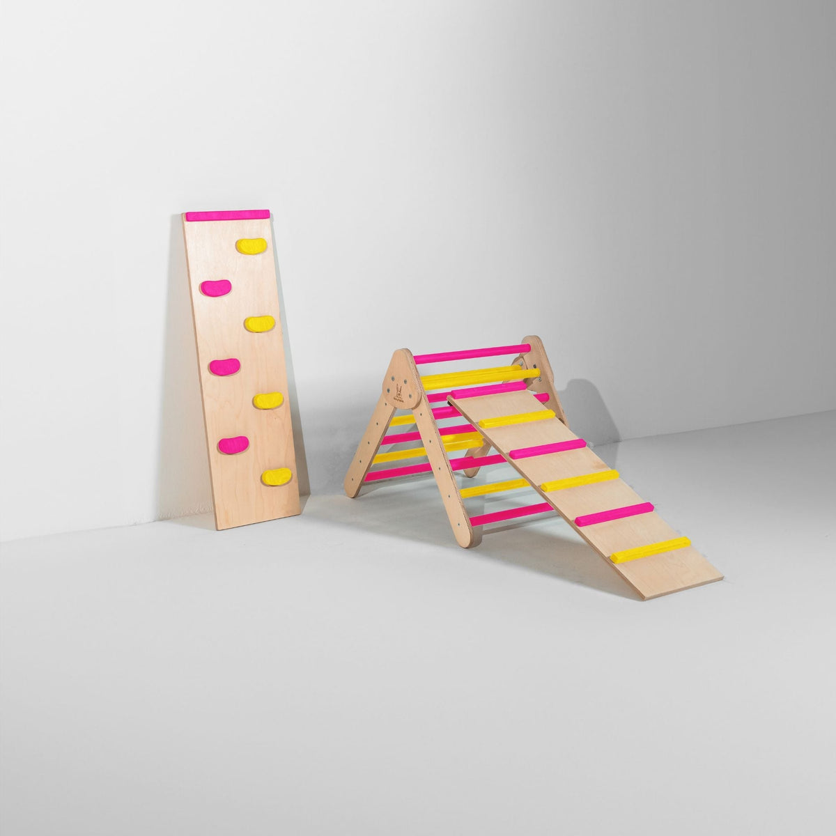 Small pink and yellow triangle with attached ladder ramp and a climbing-hold ramp beside it.