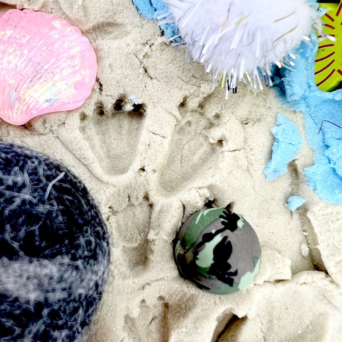 Animal-shaped impressions in sand beside miniature eggs and ocean-themed decorations