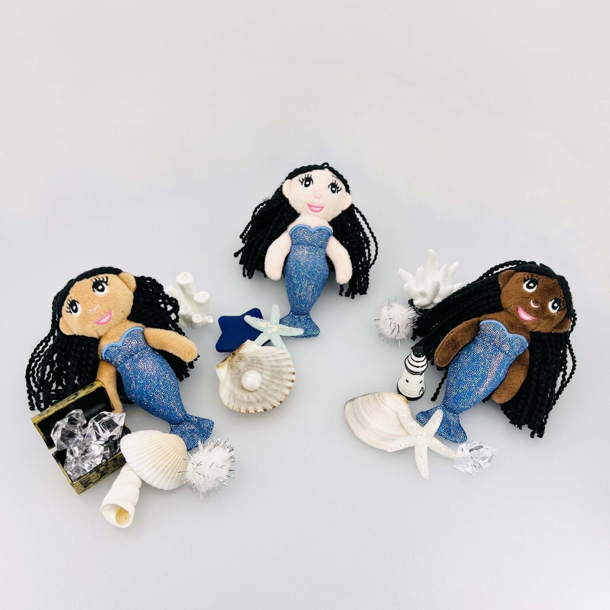 Three Mystical Mermaid fabric doll options displayed with shells and ocean accessories