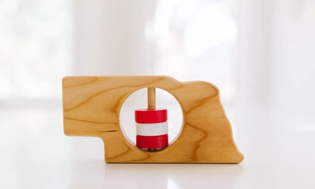 Bannor Toys Nebraska State Wooden Baby Rattle, showing state-shaped cherry-wood body and colored rattle discs