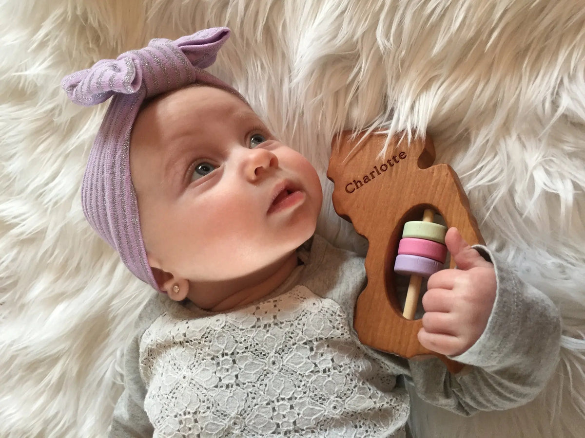 Lifestyle photo showing a wooden state rattle with a child