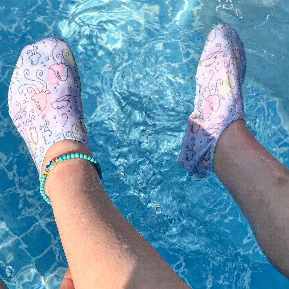 Jellyfish-print water shoes worn with feet held over pool water.