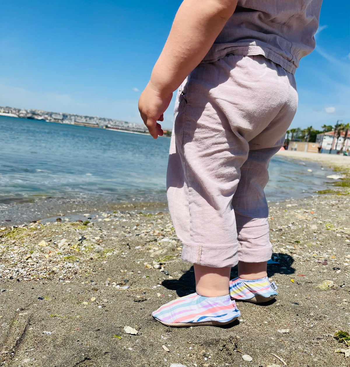 Side view of striped water shoes worn on a beach.