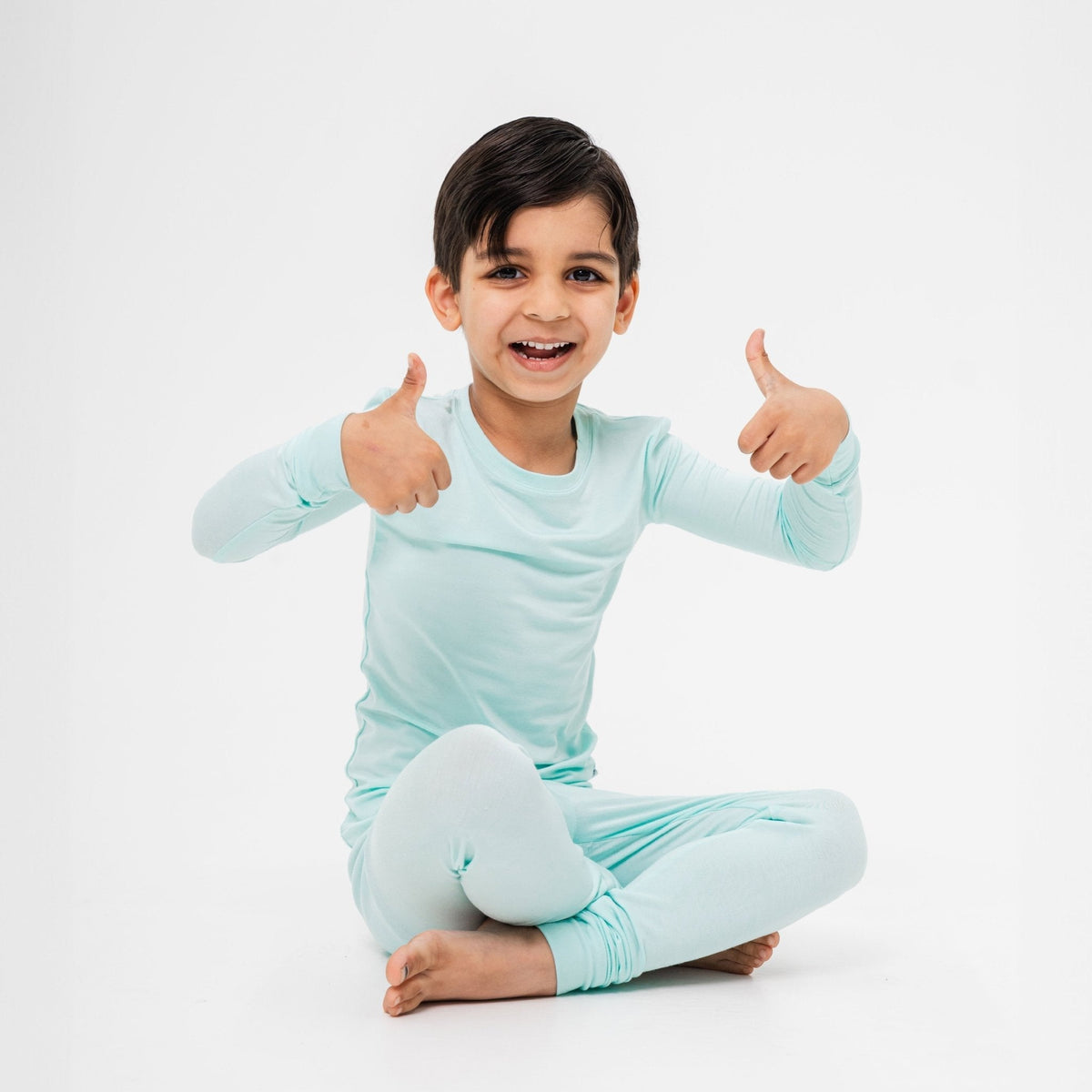 Child seated in Bam & Stitch Ocean Breeze Long Sleeve Pajamas.