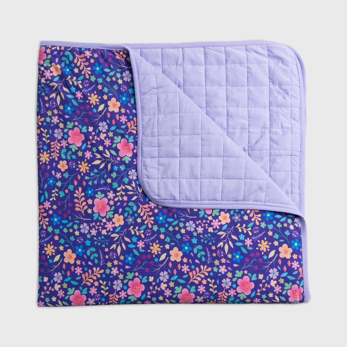 Bam & Stitch Orchid Gardens Blanket laid flat with one corner turned back to show the quilted reverse.