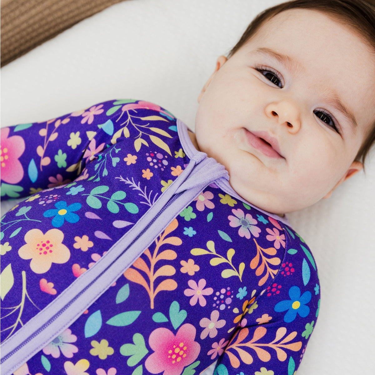 Close-up of a baby lying on their back in Bam & Stitch Orchid Gardens Convertible Romper.