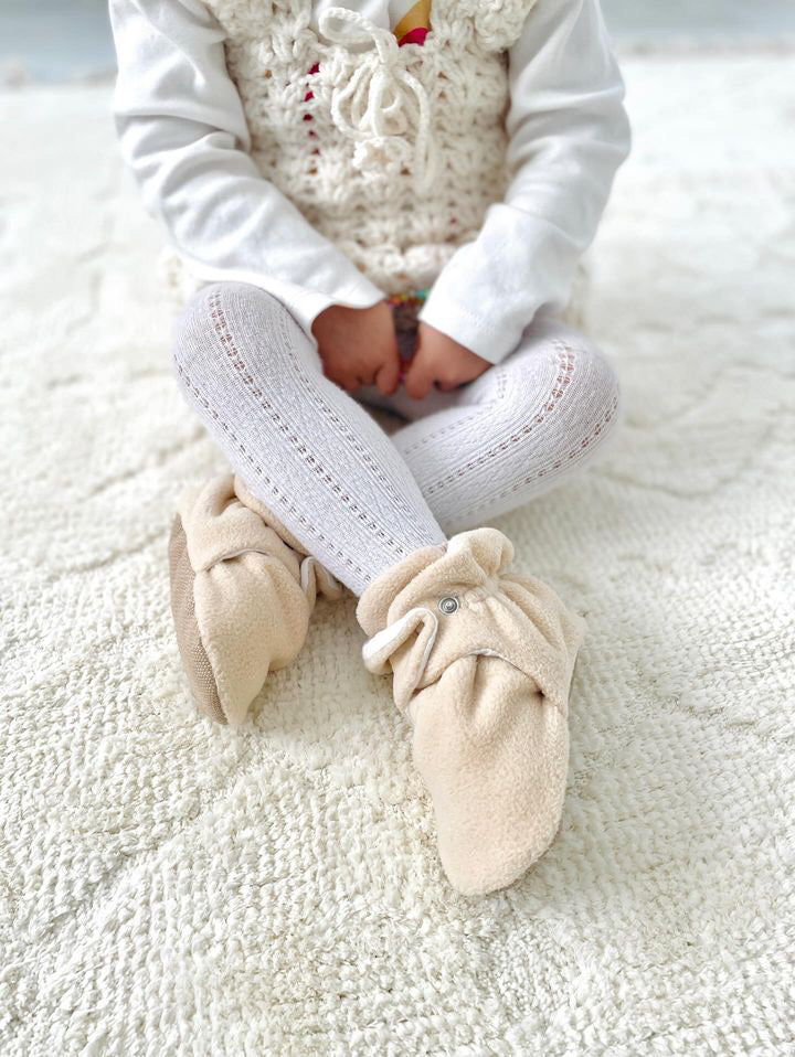 Close-up of beige booties worn with white tights.