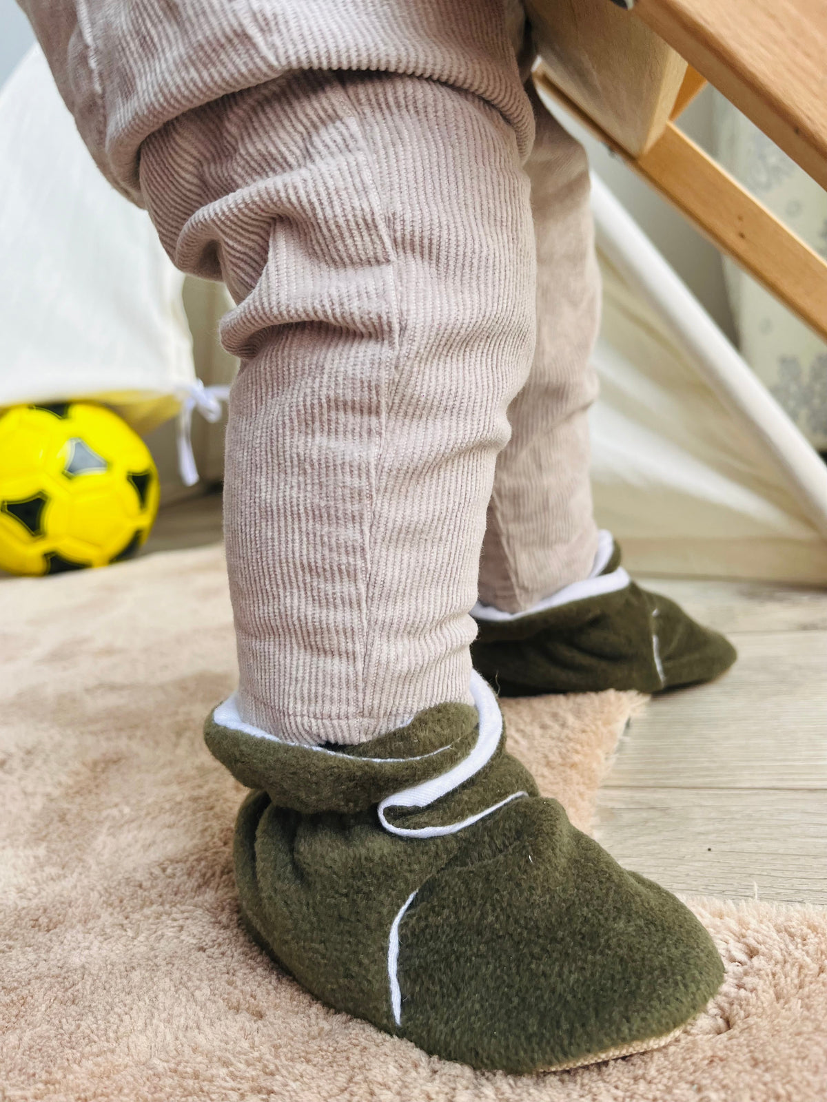 Side close-up of olive booties worn while standing.