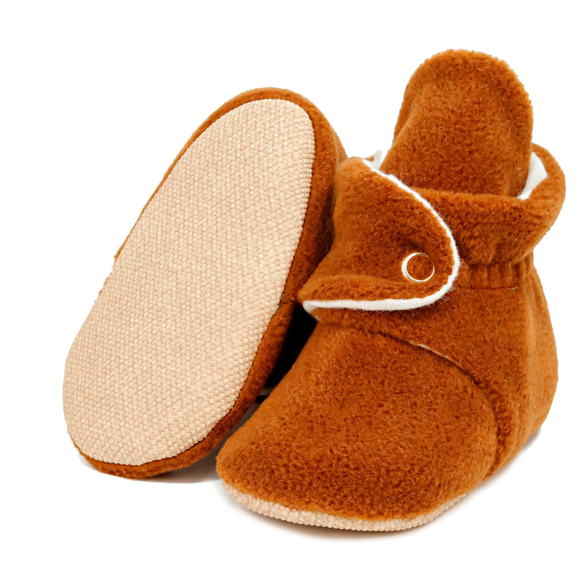 Warm brown fleece-texture baby booties with snap straps and tan soles, with one sole facing the camera on a white background.