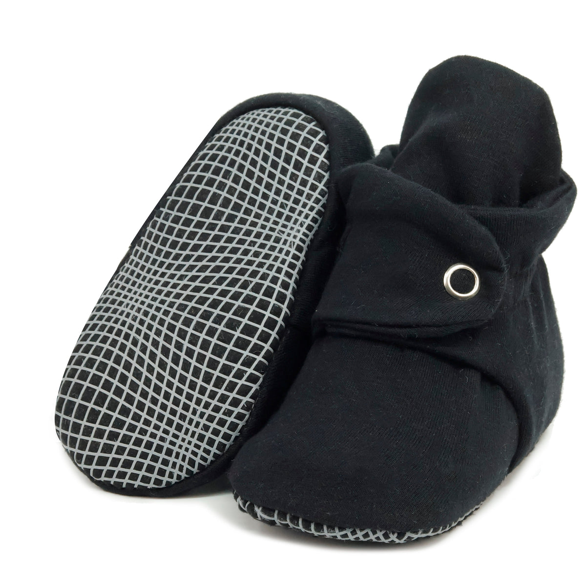 Black fabric baby booties with snap straps and gray grip soles, with one sole facing the camera on a white background.