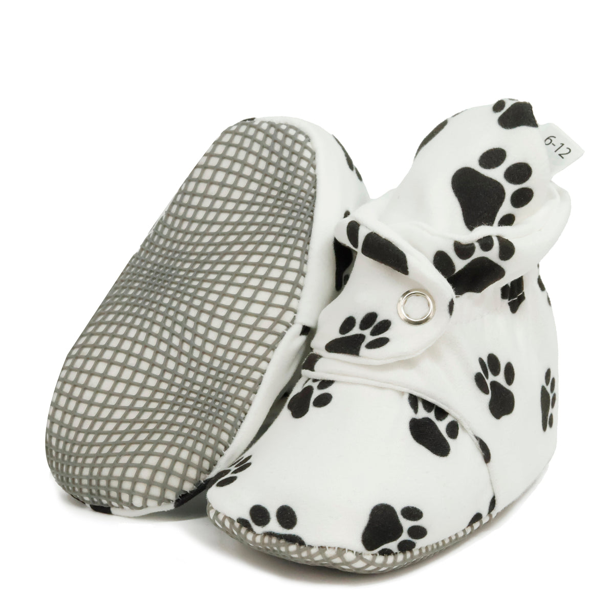 White baby booties with black paw prints and snap straps, with one sole facing the camera on a white background.