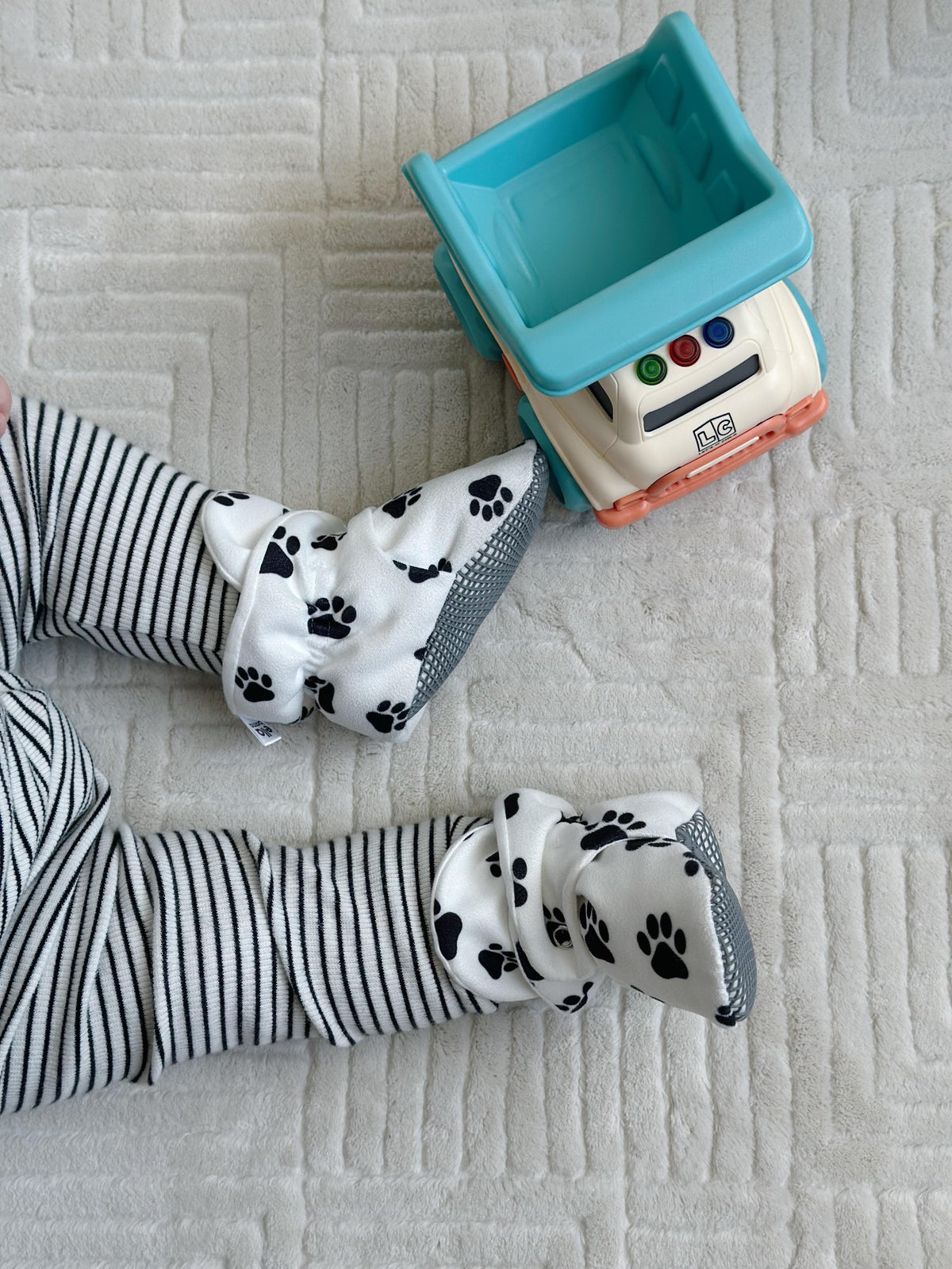 Paw-print booties worn beside a toy truck.