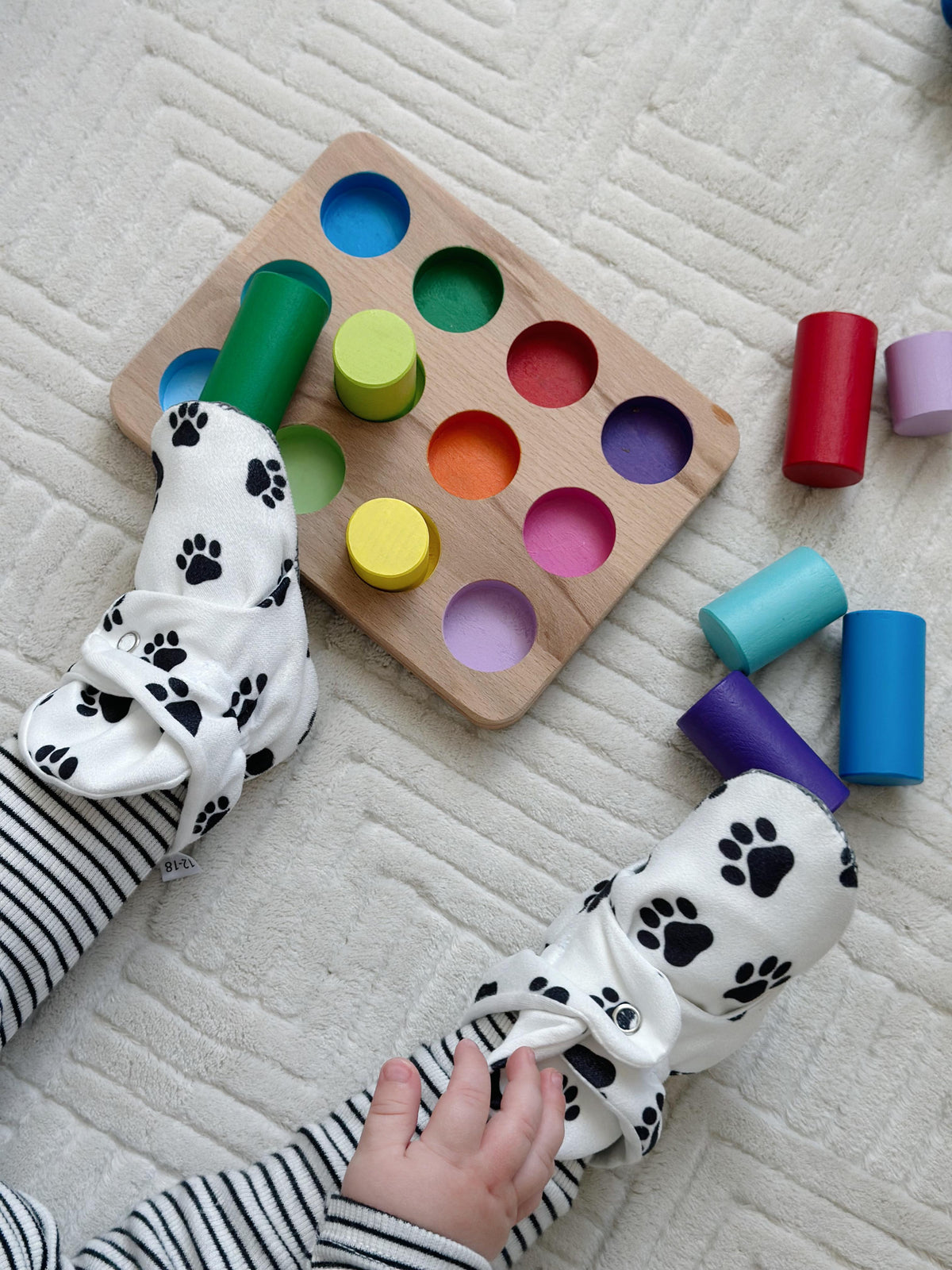 Paw-print booties worn beside a wooden shape-sorting toy.