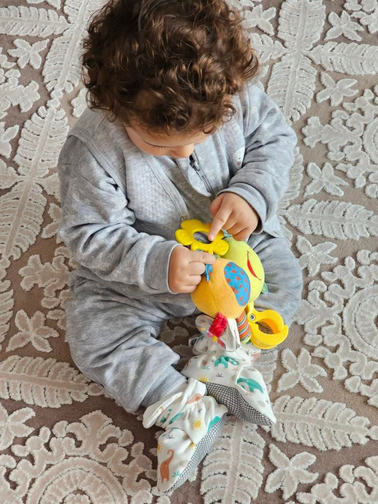 Overhead view of a child wearing elephant-print booties and holding a toy.