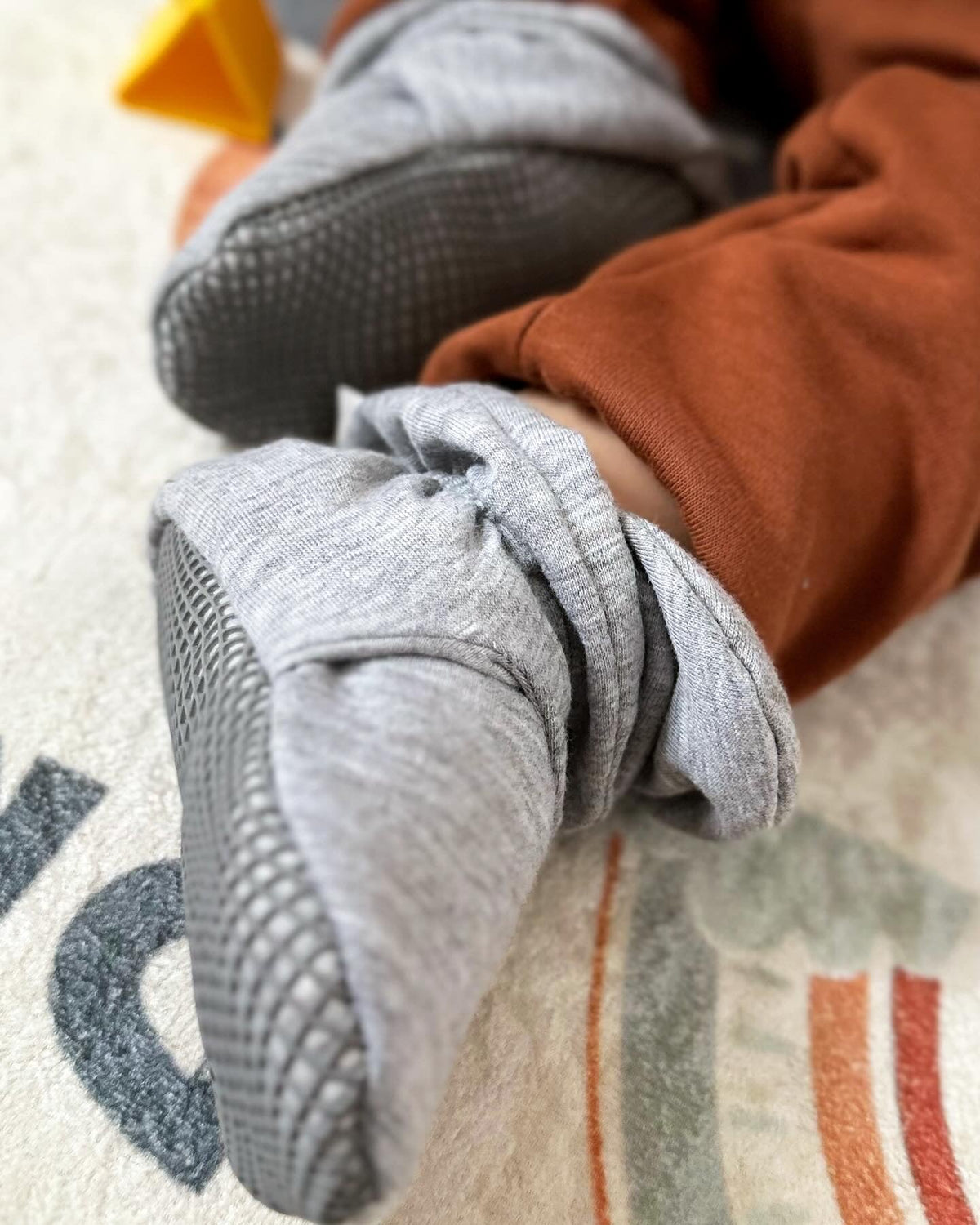 Close-up of gray booties worn by a seated child.