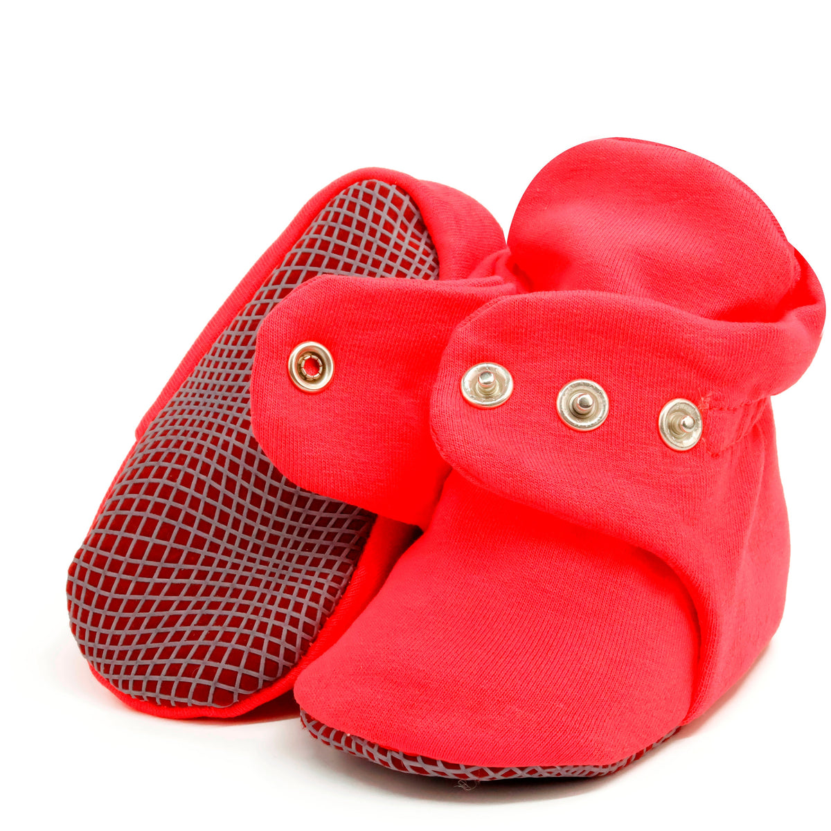 Bright red fabric baby booties with snap straps and gray grip soles, showing one sole and an open snap strap on white.