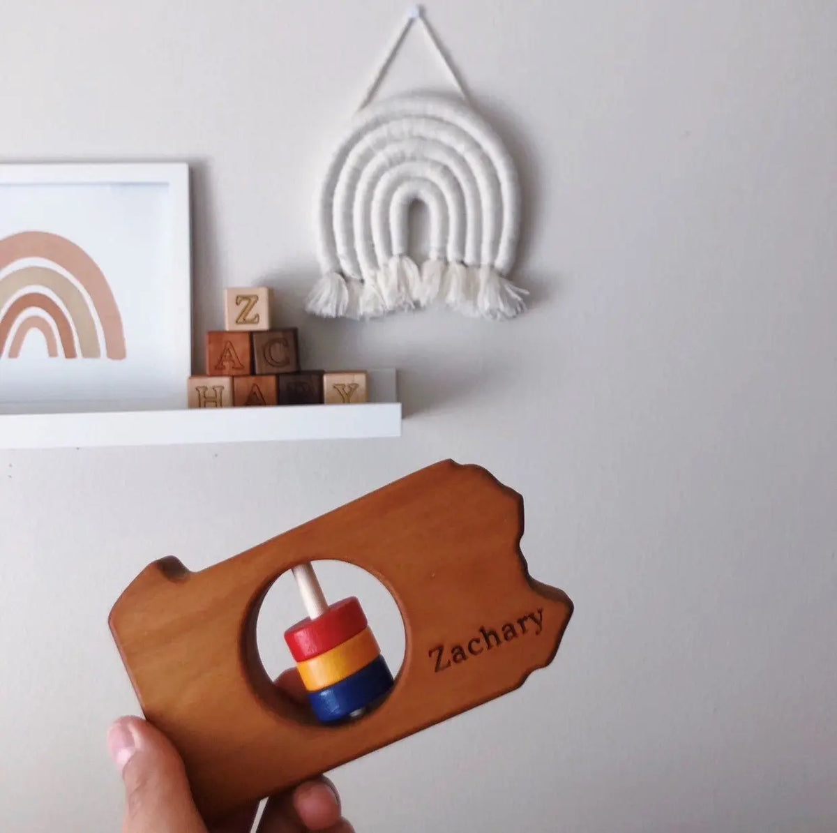 Lifestyle photo showing a wooden state rattle with a child