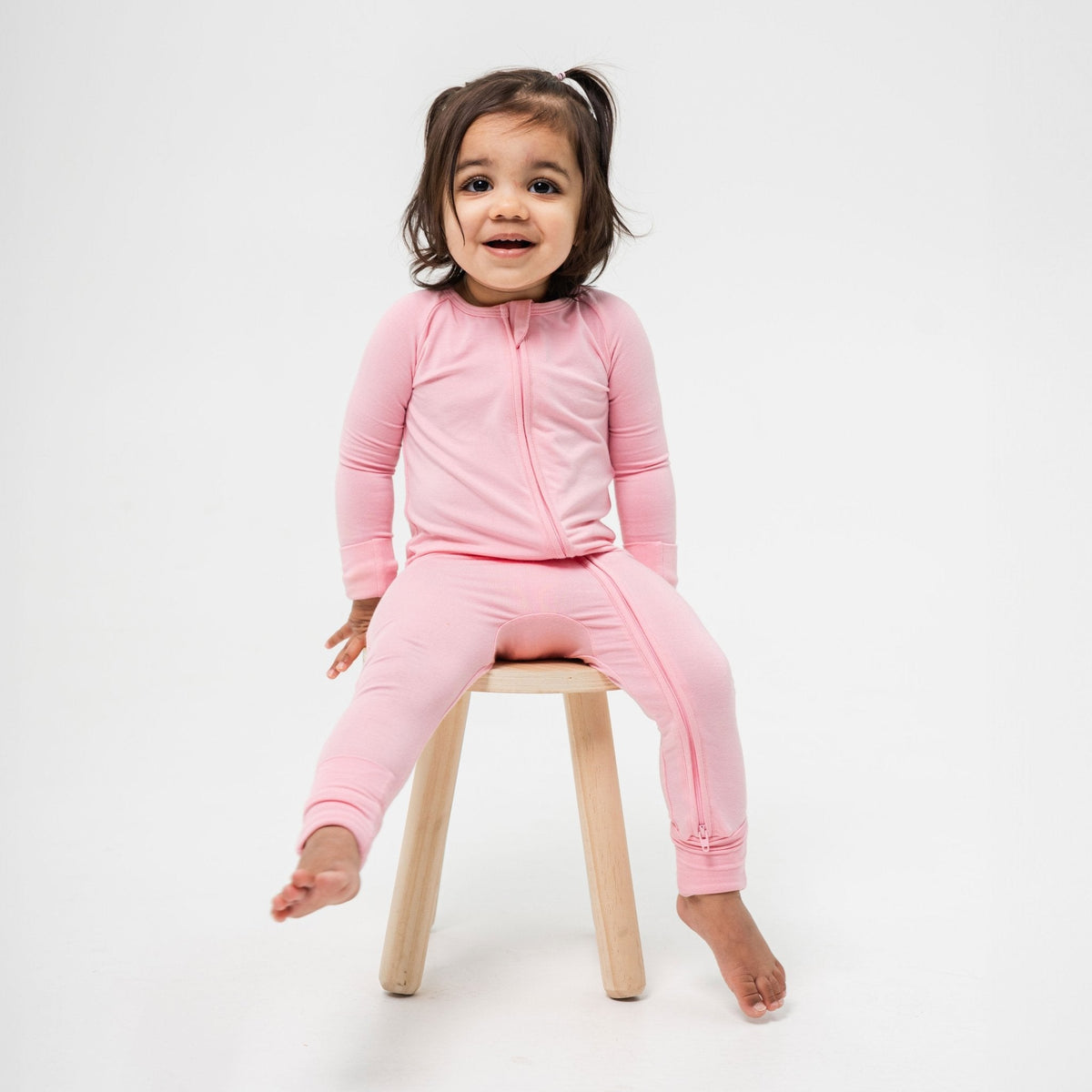 Child sitting on a stool in Bam & Stitch Pink Blossom Convertible Romper.