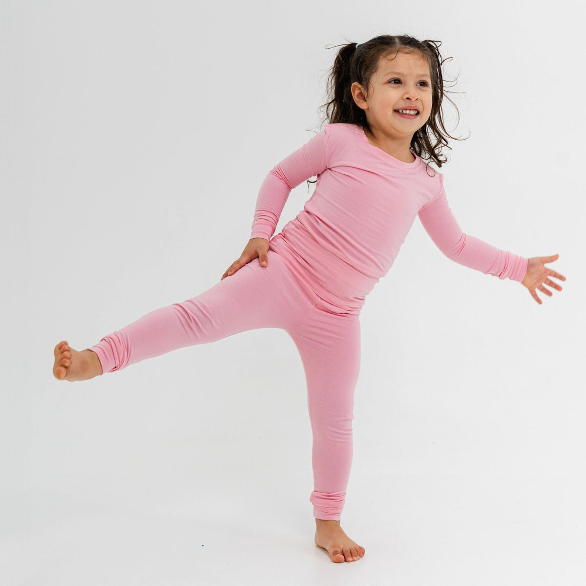 Child balancing with one leg raised while wearing Bam & Stitch Pink Blossom Long Sleeve Pajamas.