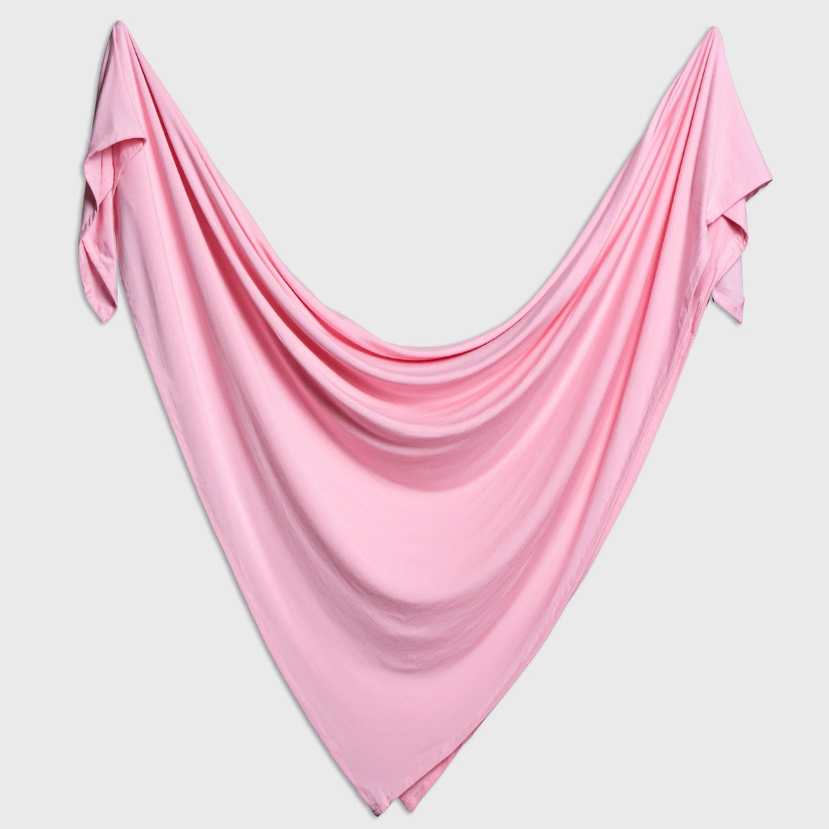 Bam & Stitch Pink Blossom Swaddle draped open to show the solid color.