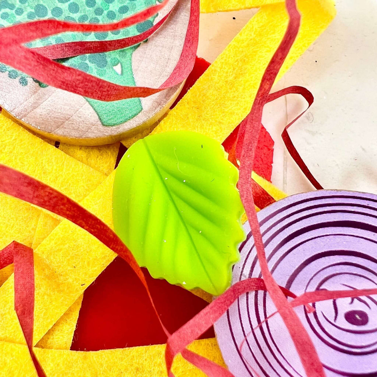Pizza topping discs and green leaf decoration among red and yellow strips
