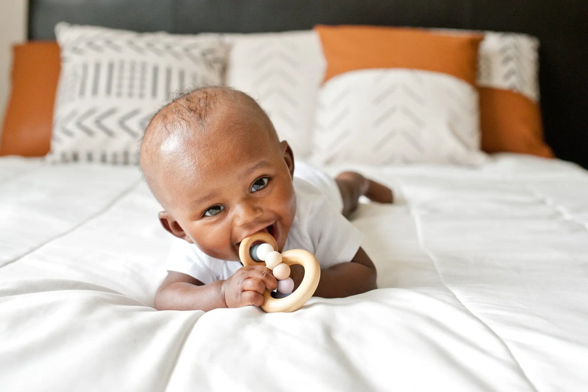 Lifestyle photo showing a wood and silicone teether with a child