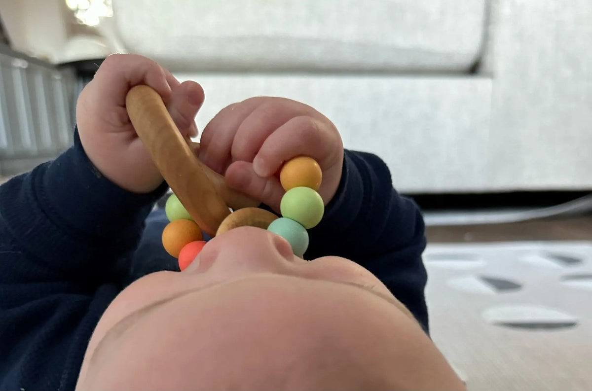 Lifestyle photo showing a wood and silicone teether with a child