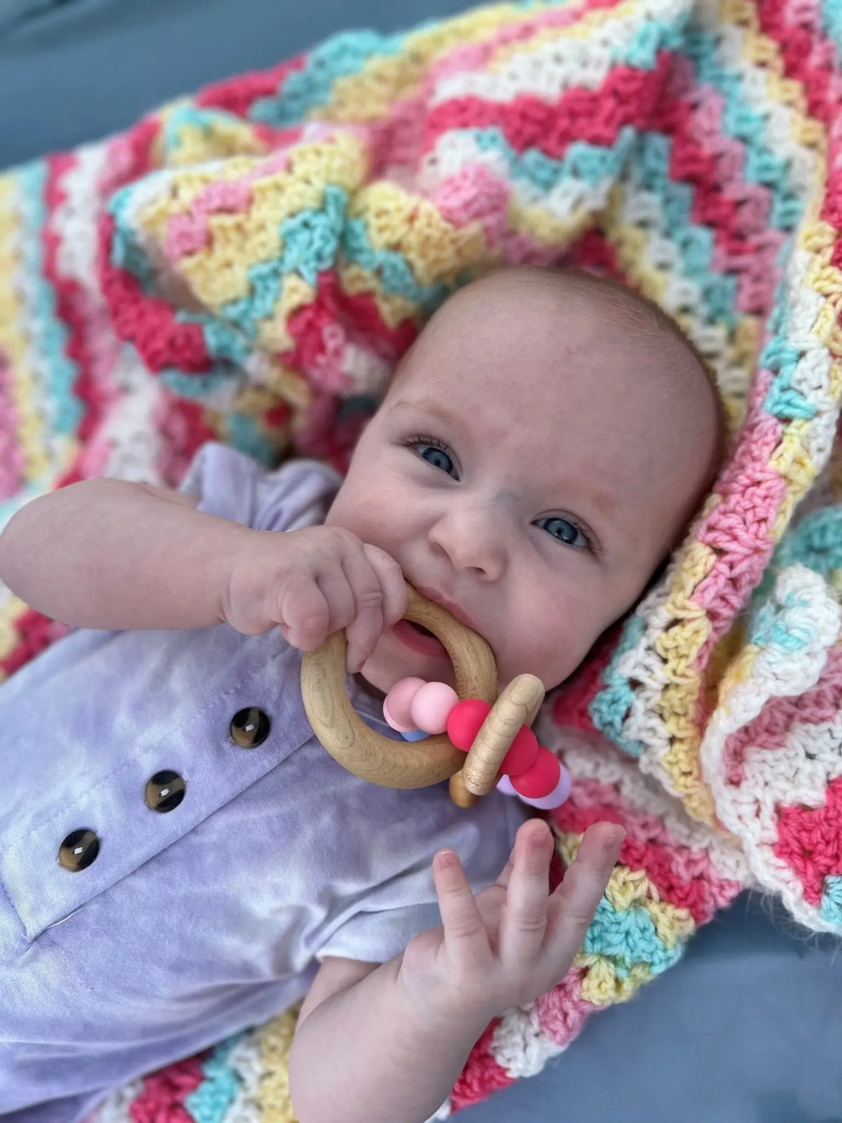 Lifestyle photo showing a wood and silicone teether with a child