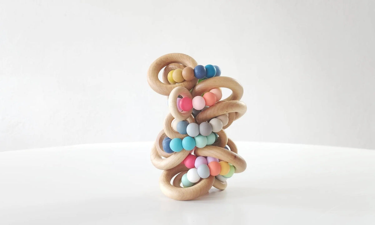 Several Saturn Ring Teethers stacked to show their wood rings and silicone color variations