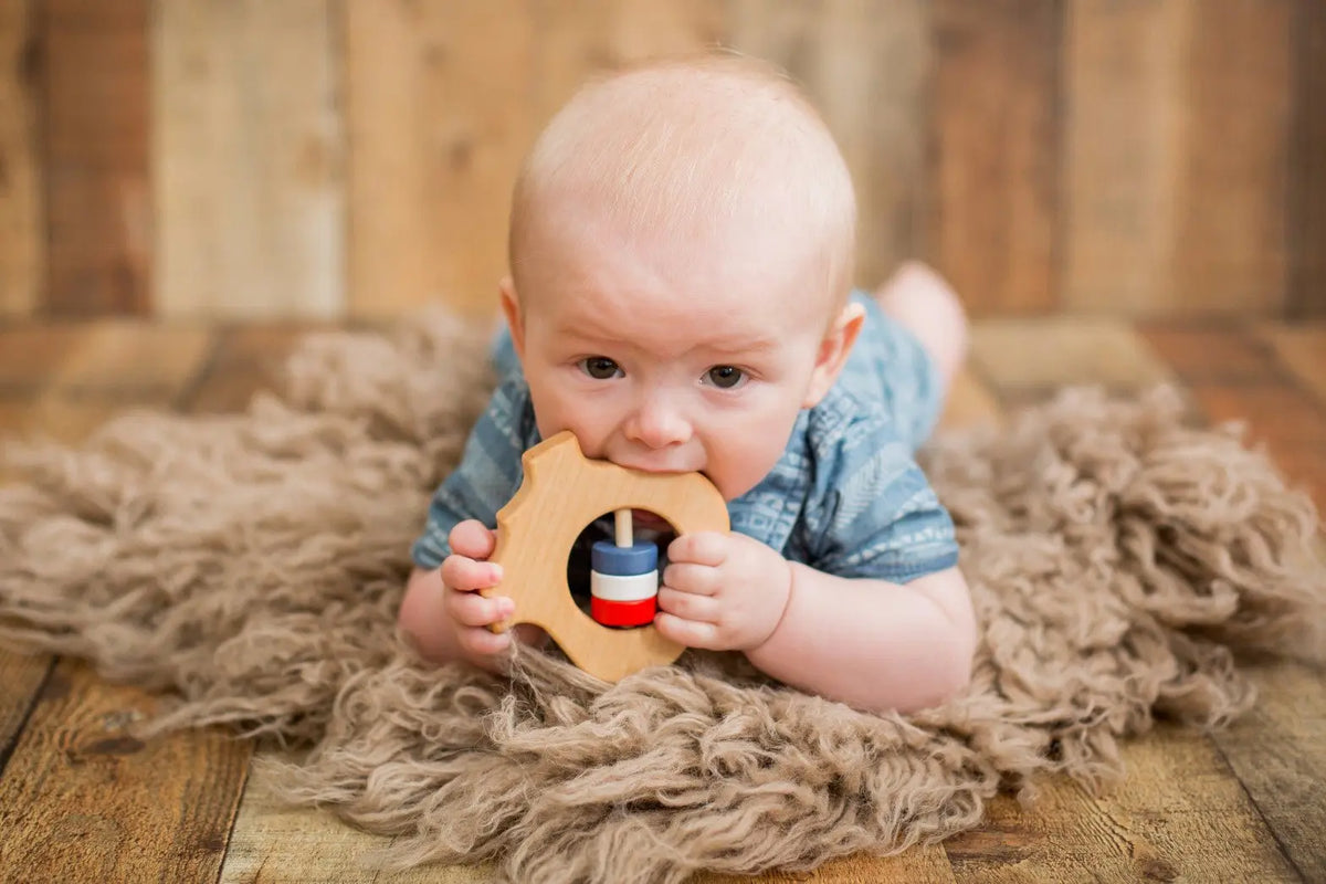 Lifestyle photo showing a wooden baby rattle with a child