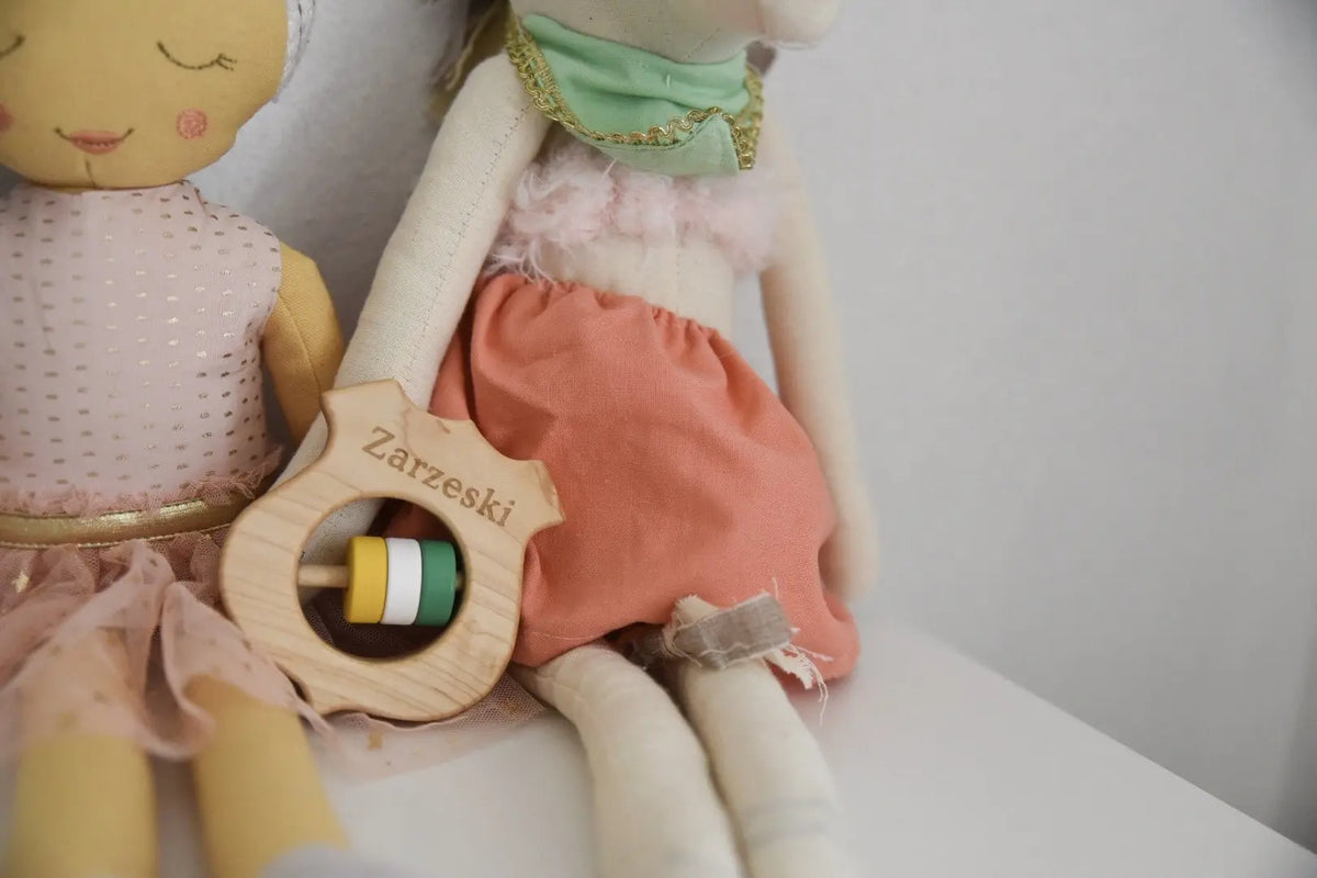 Wooden shield rattle displayed with soft dolls
