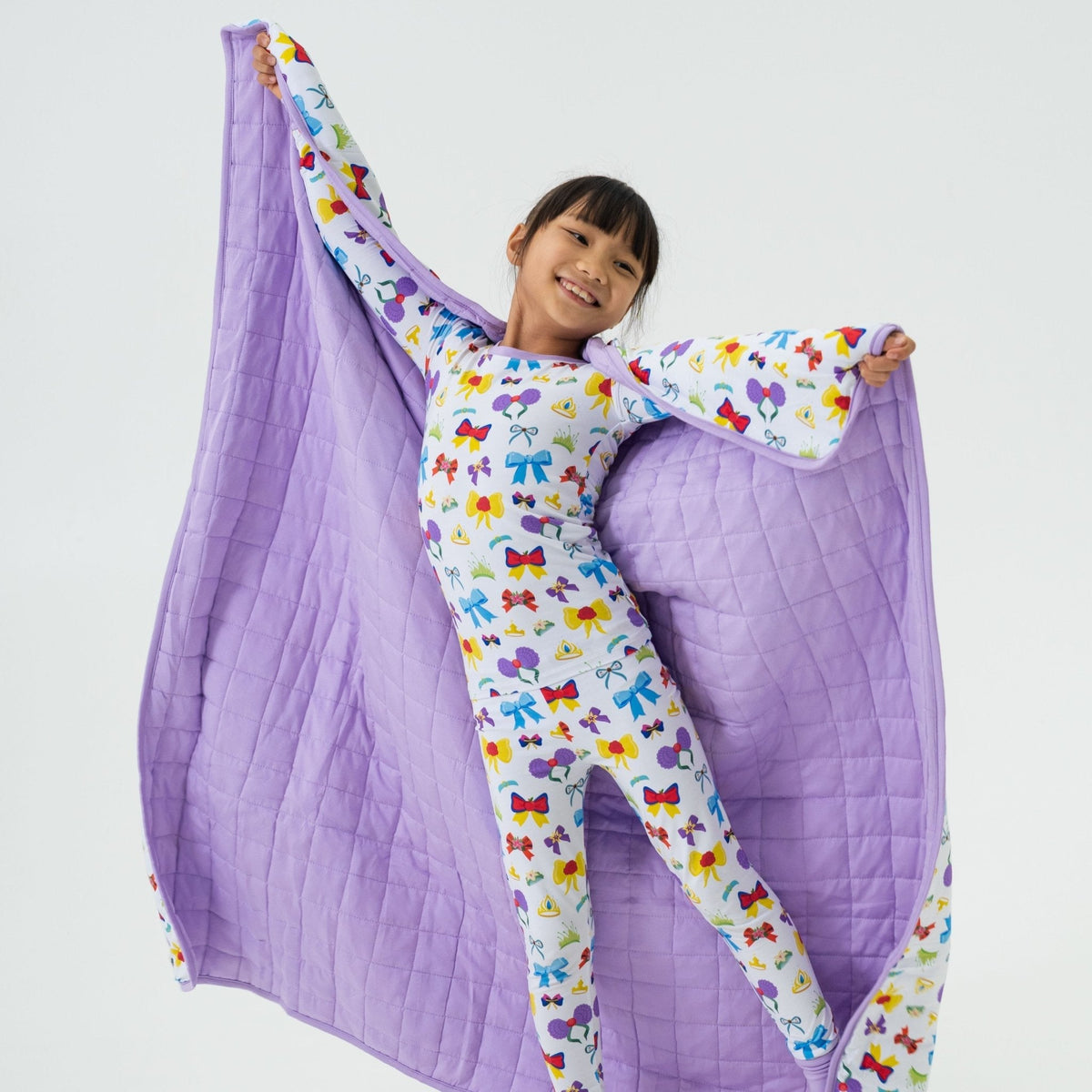 Child raising one corner of Bam & Stitch Sparkle & Reign Blanket to reveal its quilted reverse.