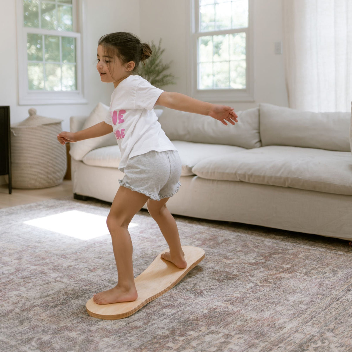 Child turning sideways on a pale Spinzee board with arms extended.