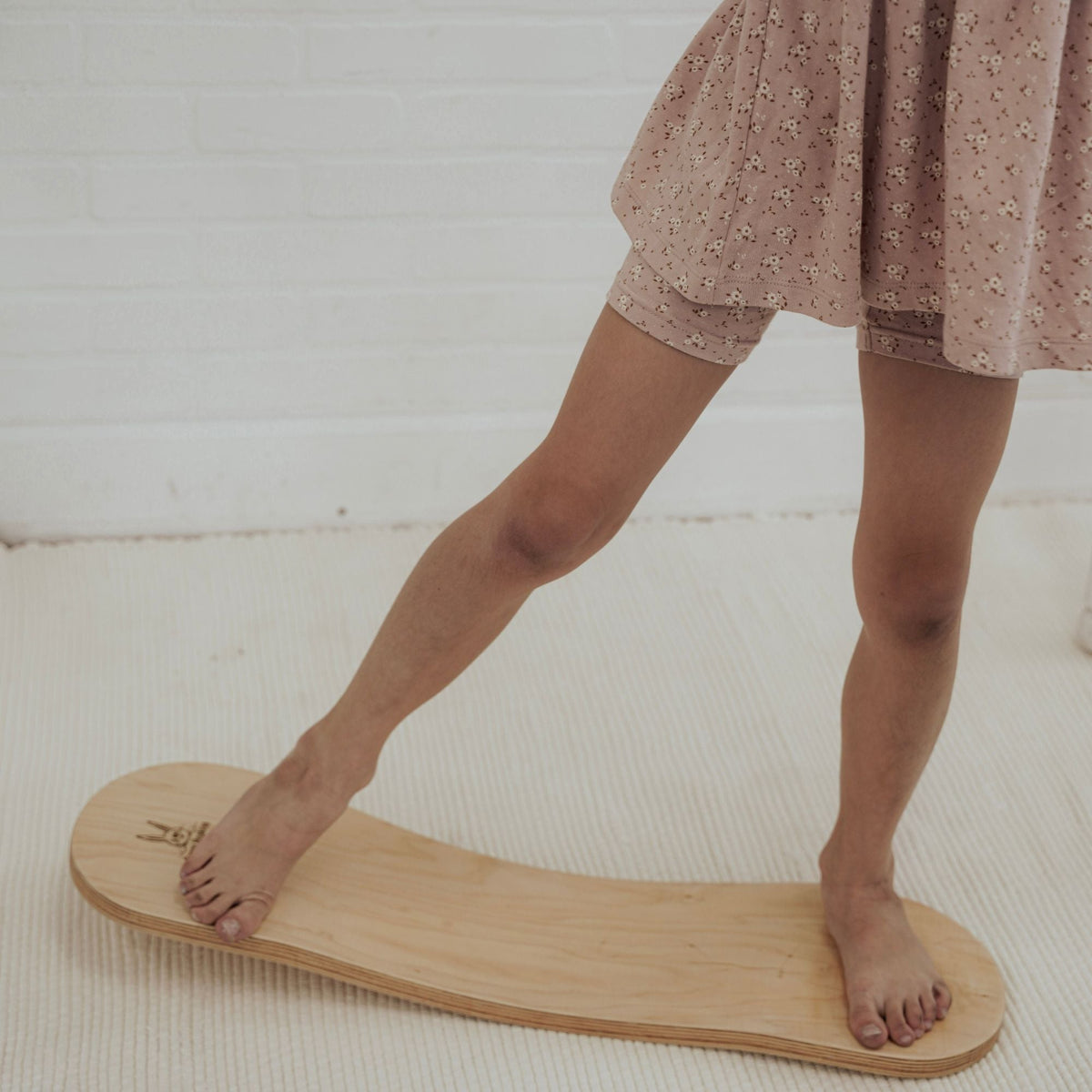 Close-up of a child balancing barefoot on a pale Spinzee board.