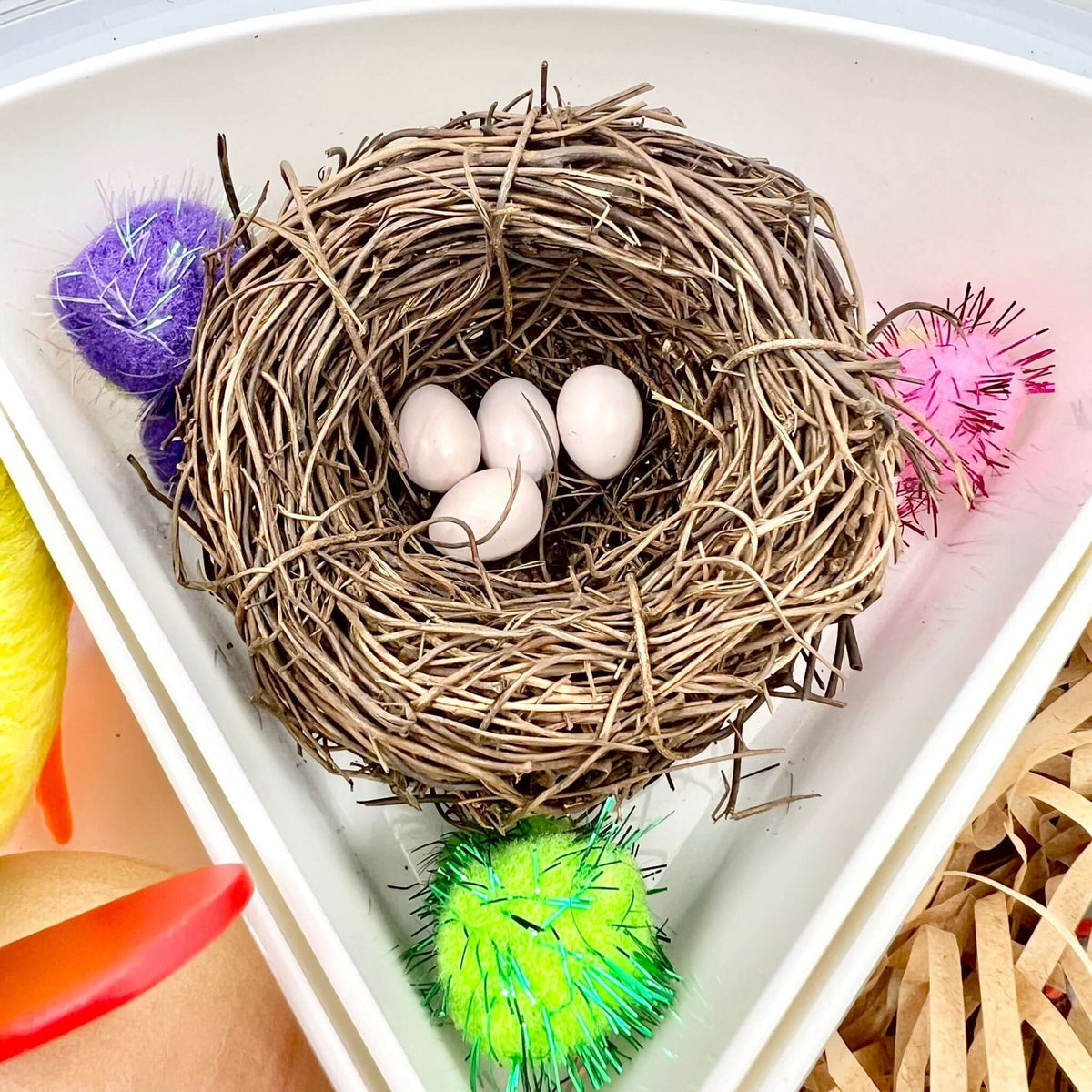 Small nest holding white eggs beside colorful pom-poms in the Spring Garden set