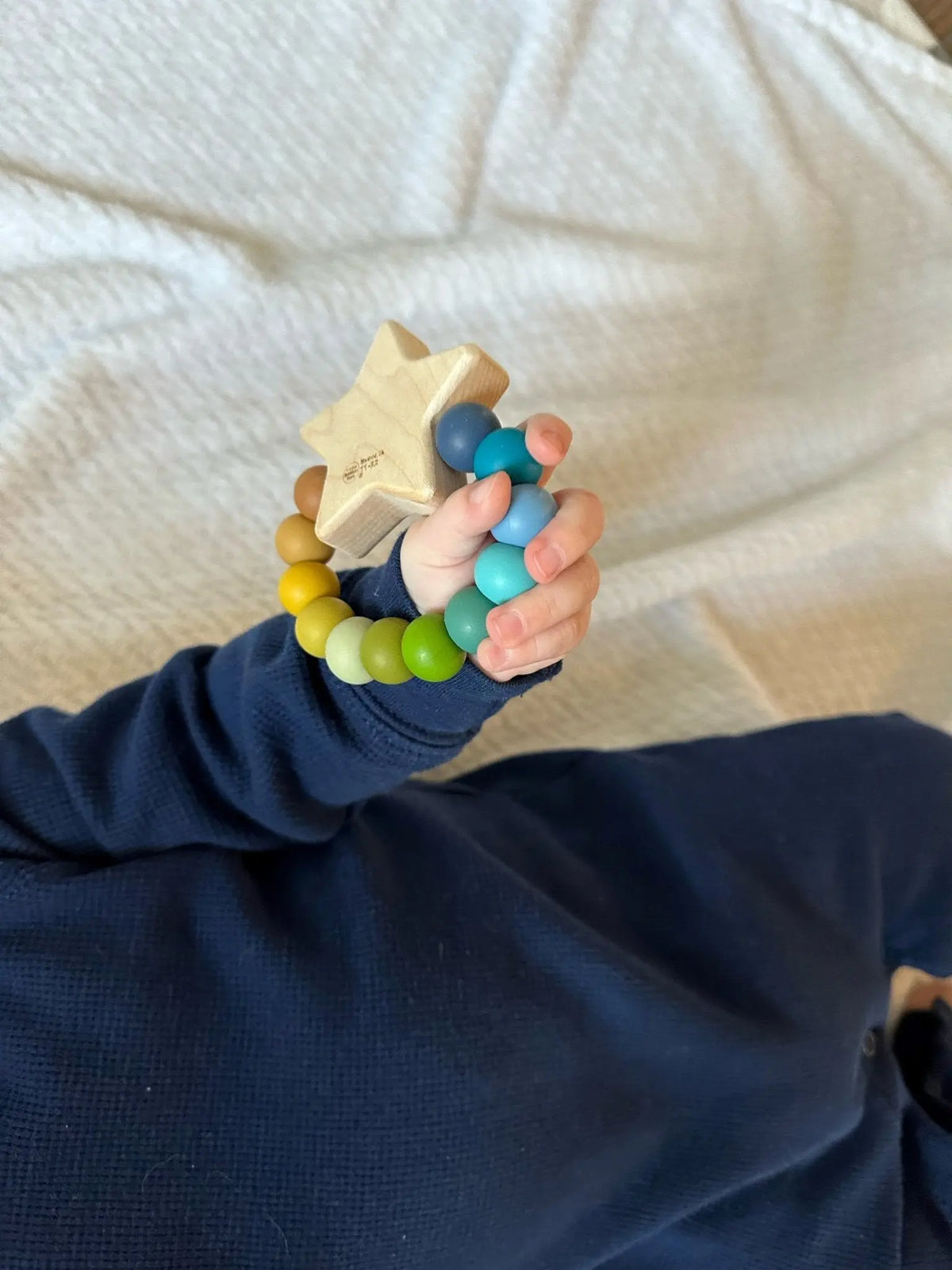 Lifestyle photo showing a wood and silicone teether with a child