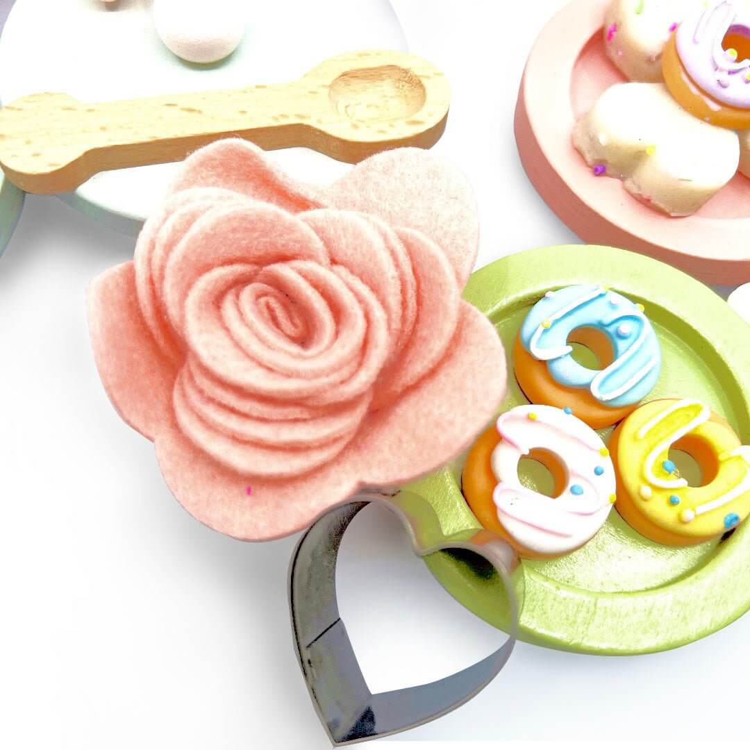 Pink flower decoration, heart cutter and miniature donuts on a green saucer