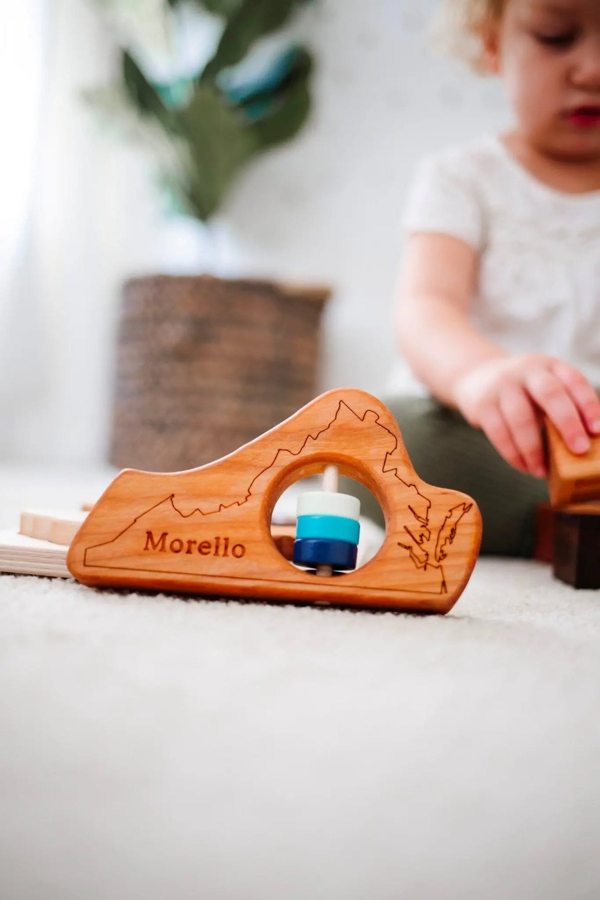Lifestyle photo showing a wooden state rattle with a child