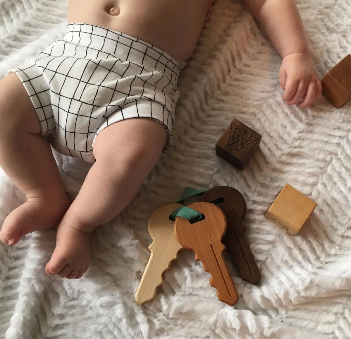 Lifestyle photo showing wooden toy keys with a child