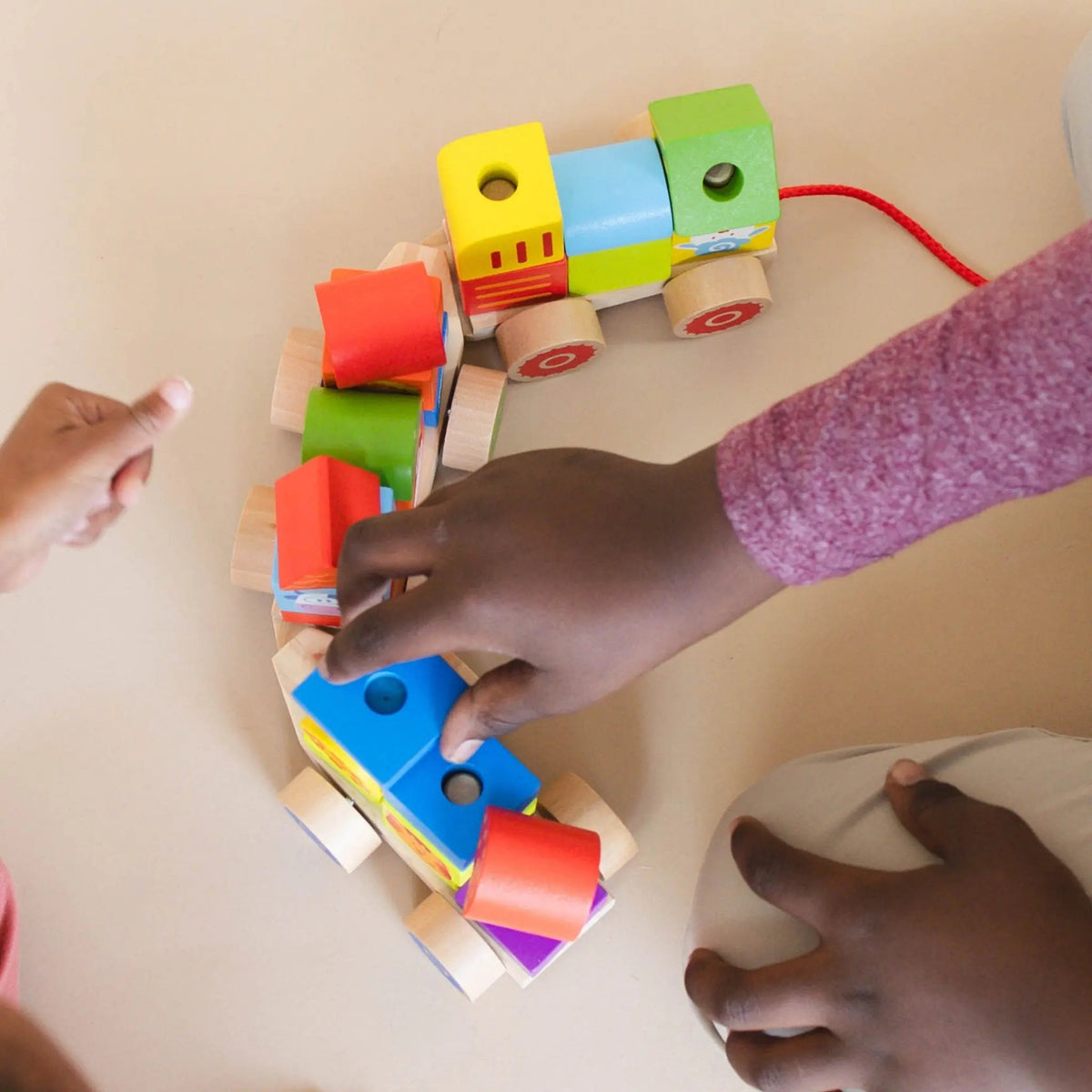 SpiritnSprout: Close-up of a child placing colored blocks on wooden train cars