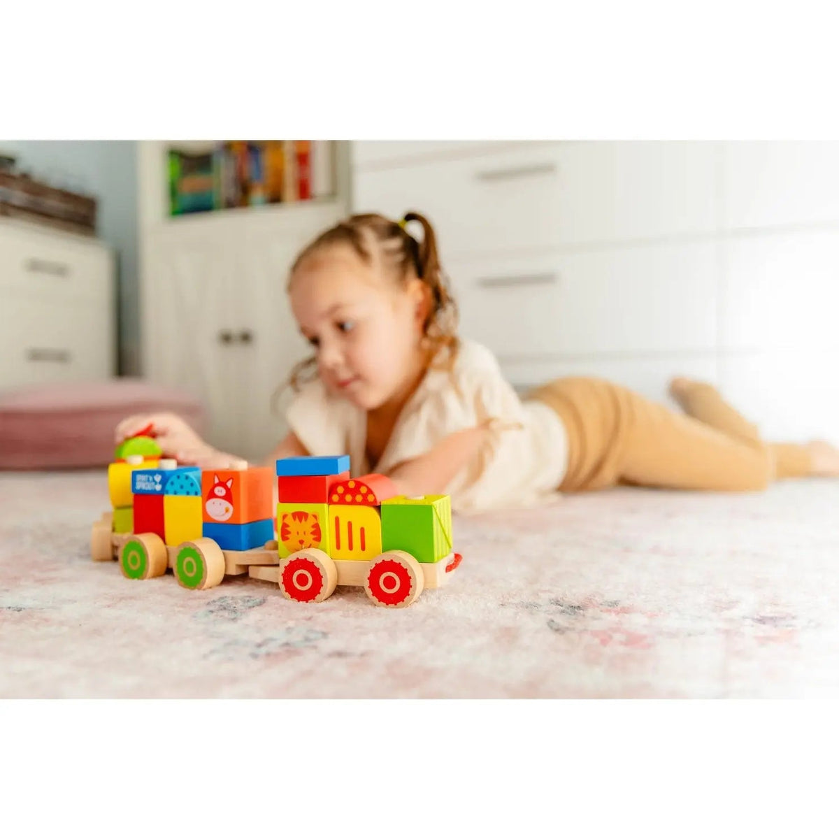 SpiritnSprout: Child lying on a rug and playing with the stacking train