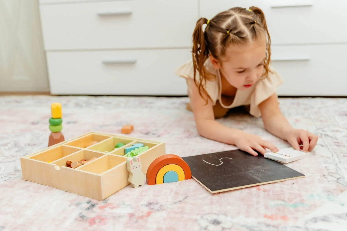 SpiritnSprout: Child drawing on the chalkboard lid beside the forest pieces