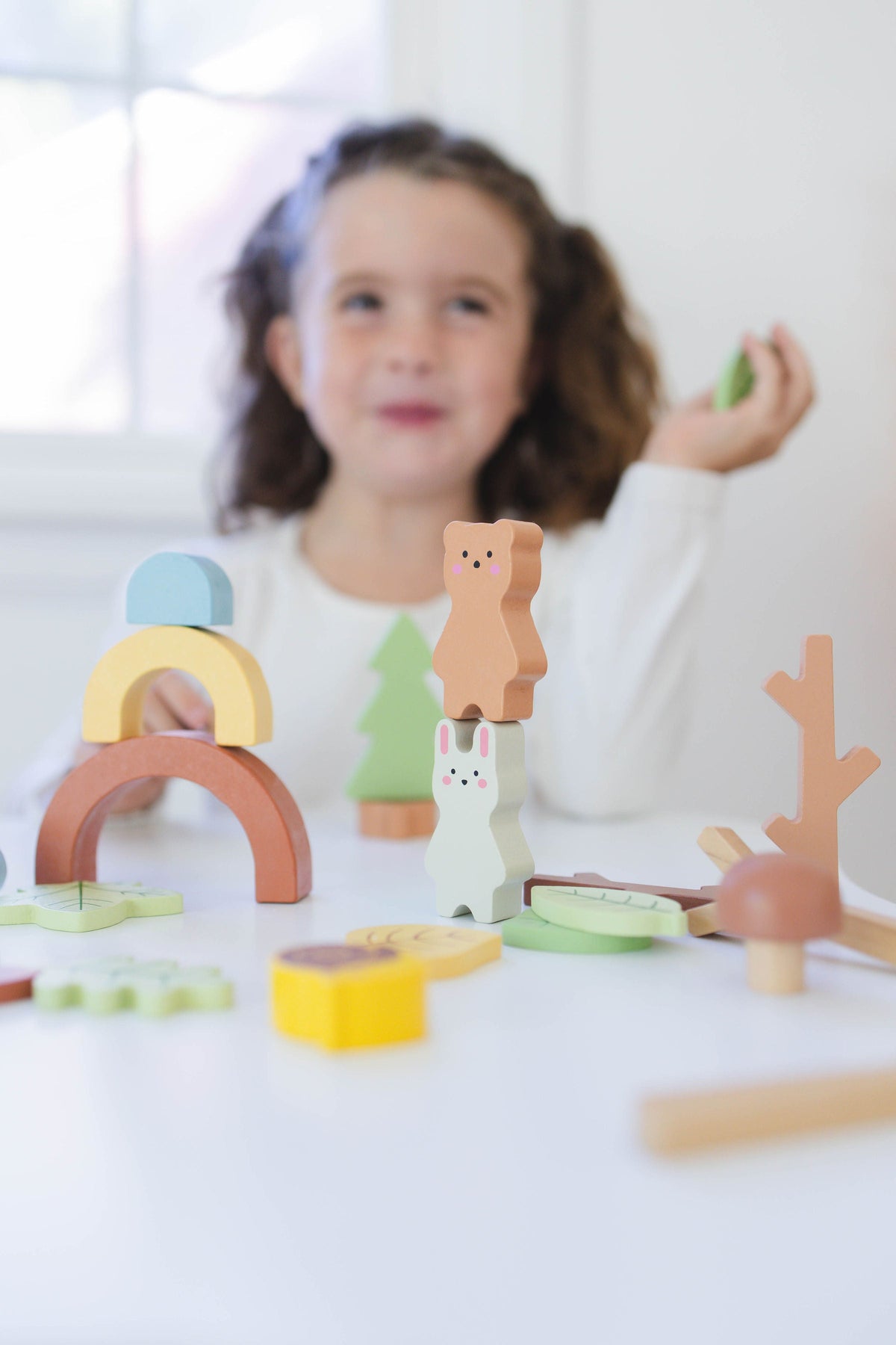 SpiritnSprout: Child holding forest pieces while building a woodland scene