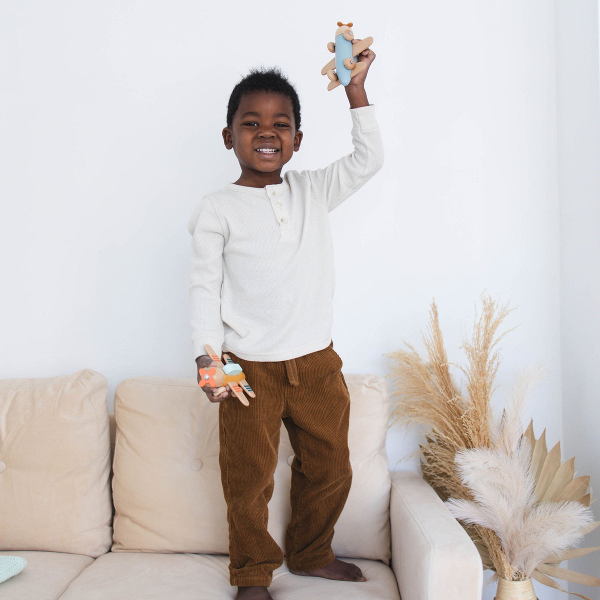 SpiritnSprout: Child holding the blue and gold wooden airplanes