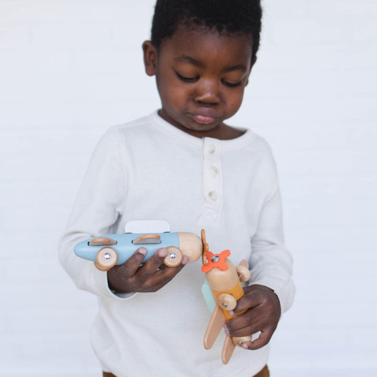 SpiritnSprout: Child examining blue and gold toy airplanes