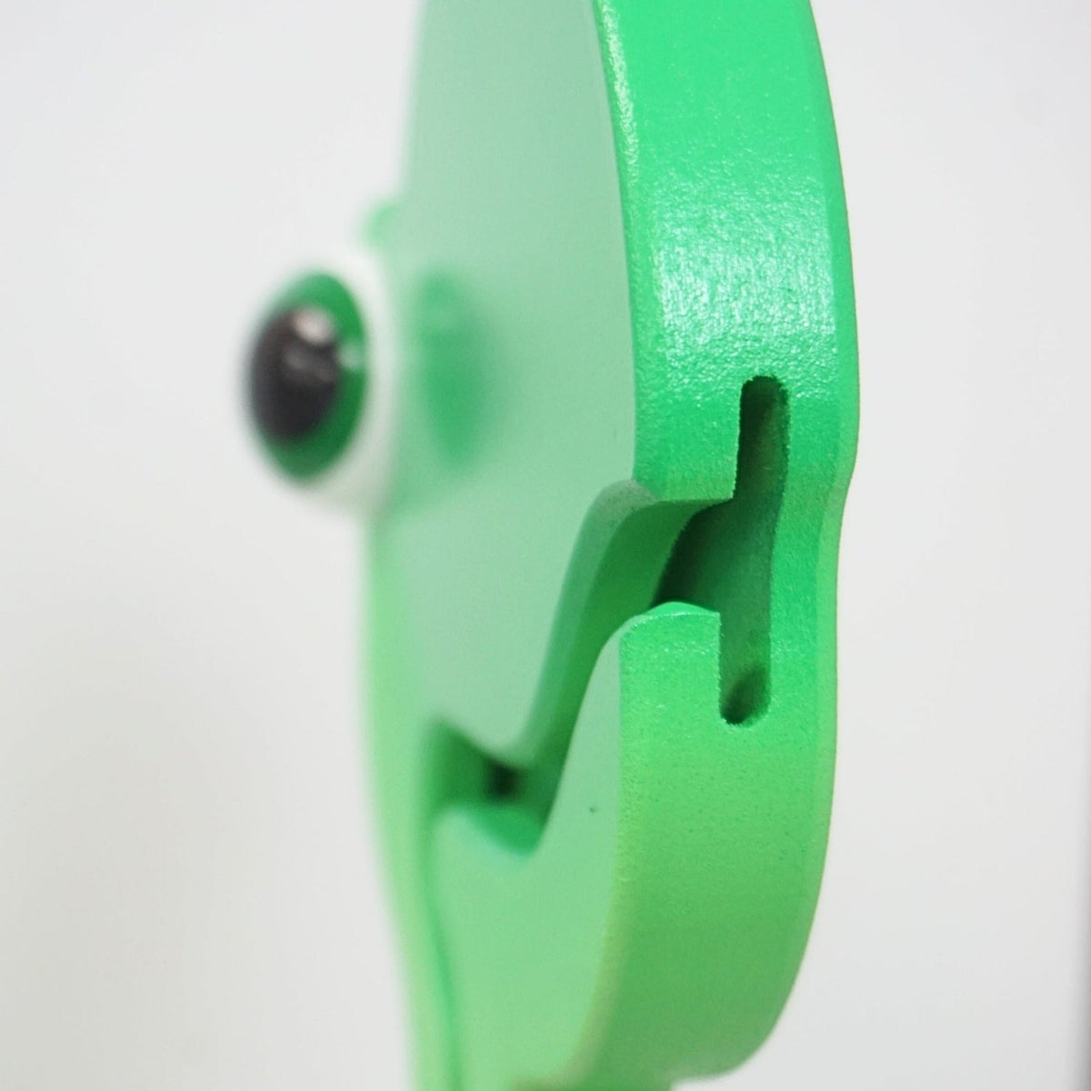 Edge-on close-up of the green dinosaur coin-entry slot