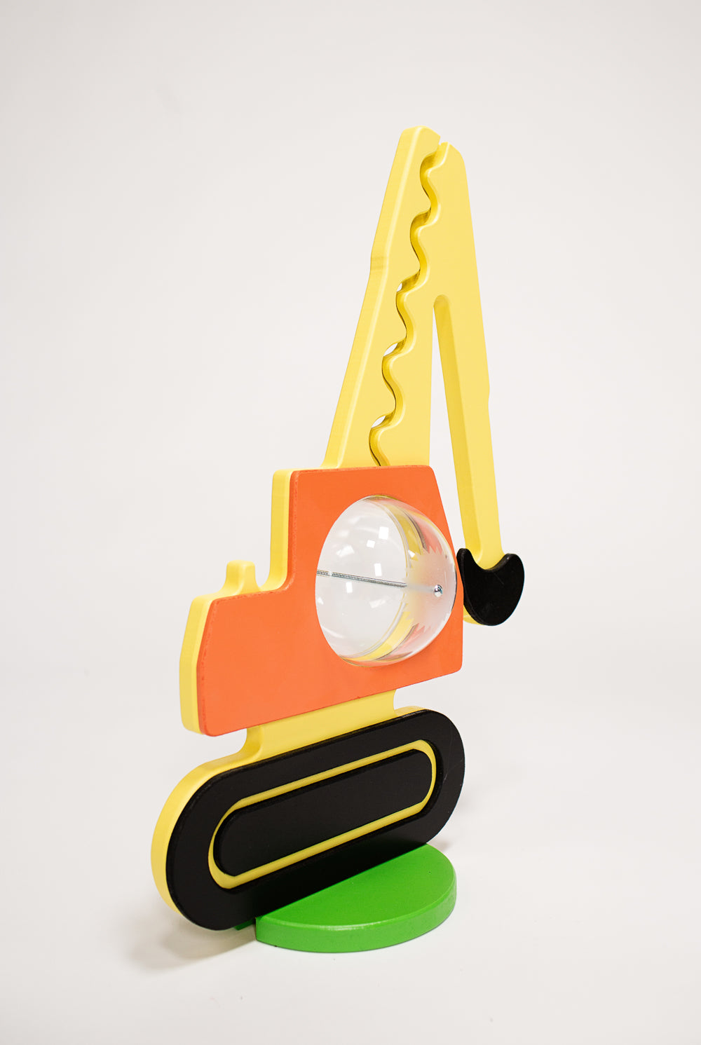 Angled view of the excavator coin bank with raised yellow arm and black bucket