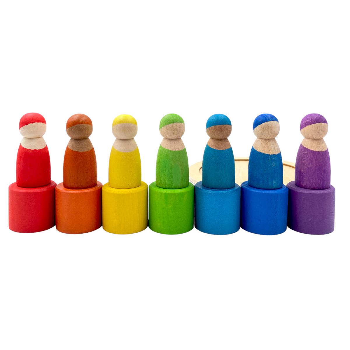 Seven wooden peg dolls standing on inverted matching bowls in rainbow order