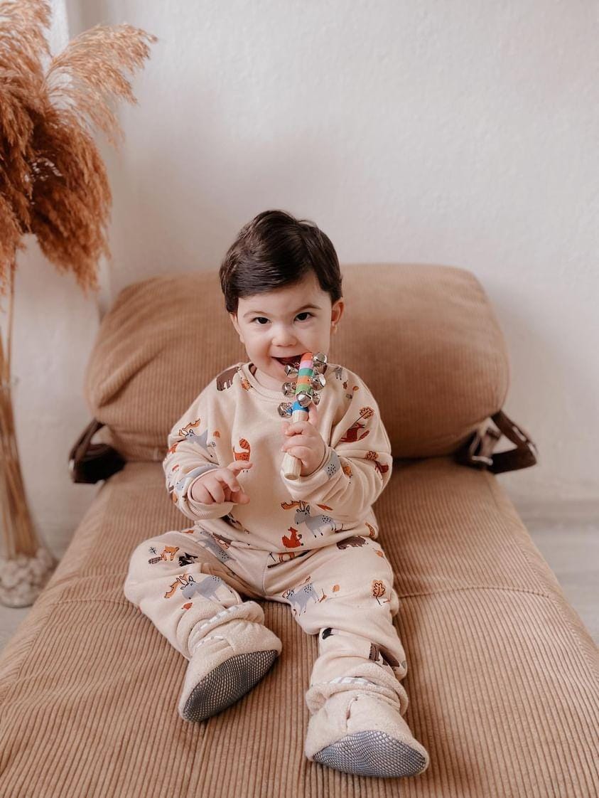 Child seated on a sofa wearing pajamas and pale gray footwear, closer view.